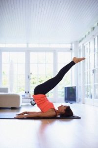 Mid adult woman lying on back practicing yoga in living room